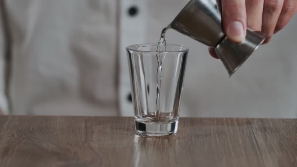 Le barman verse la sambuca du jigger au verre à cocktail