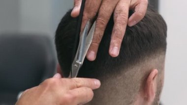 Profesyonel kadın kuaför, erkek saçını tarıyor ve kesiyor. Yaklaşın, ağır çekim.