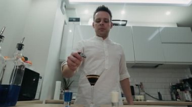 Barmen kokteyli ateşe veriyor, alkollü içecekle tarçın yakıyor.