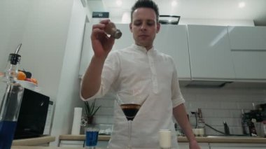 Barmen yanan bir alkollü kokteylin üzerine tarçın serper.