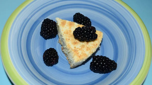 Cheesecake with blackberries on a blue plate