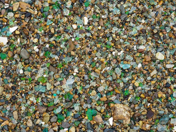 Suyla çevrilmiş bir sürü renkli cam parçasıyla taştan bir plajın dokusu..