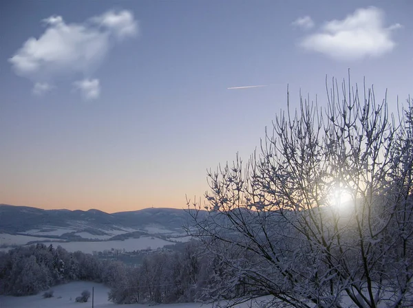 Background photo of low clouds in a mountain valley, vibrant blue and orange sky. Sunrise or sunset view of mountains and peaks peaking through clouds.