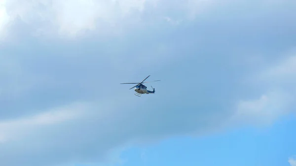 轮廓清晰的直升机在蔚蓝多云的天空中飞得又高又远 — 图库照片