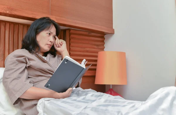 Wife thinking and read book in bedroom, lifestyle concept
