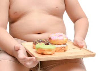 Obez şişman çocuk beyaz arka plan, abur cubur ve diyet kavramı üzerinde izole çörek tutuyor