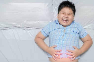 Asyalı şişman çocuk mide ağrısı ve kırmızı nokta gösteren konumdan acı acı. sağlıklı kavramı