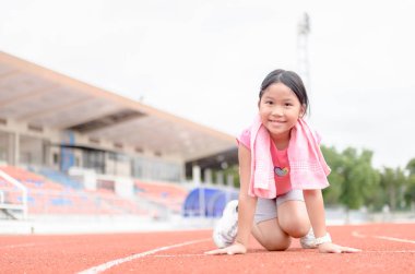 Başlama pozisyonu çalıştırmak için hazır, şirin kız. bir sprint parlak güneş ışığı ile kameraya bakarak başlamak üzere çocuk atlet. Diyet ve egzersiz kavramı
