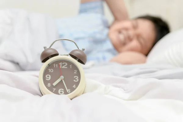 ベッドで朝に目覚まし時計の音から耳を覆う怠け者の目覚まし時計 の概念に目を覚ます — ストック写真