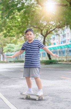 Obez çocuk öğrenmek paten kurulu fitness Park, çocuklar için etkin açık spor sürmek.