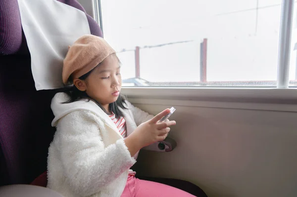 Little traveler play mobile phone in train, travel or lifestyle concept