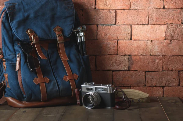 Old vintage canvas bag with vintage camera and hot on wood table, accessories hipster style, Travel concept
