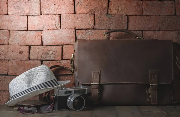 vintage leather bag with vintage camera and hat on wood table, accessories hipster style, prepare for Travel concept and vintage tone