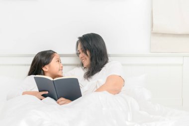 Annesi ile kızı birlikte yatağa eğitim kavramı kitap okumak