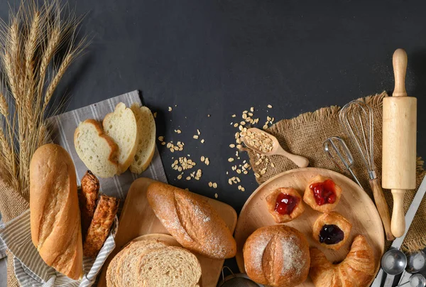 stock image Homemade breads or bun, croissant and bakery ingredients on black stone background, breakfast food concept top view and copy space