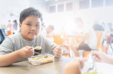 Obez şişman çocuk yeme kutu öğle yemeği içinde gıda mahkeme, 
