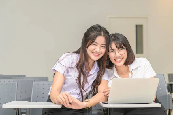 Милі студенти посміхаються і працюють з ноутбуком — стокове фото