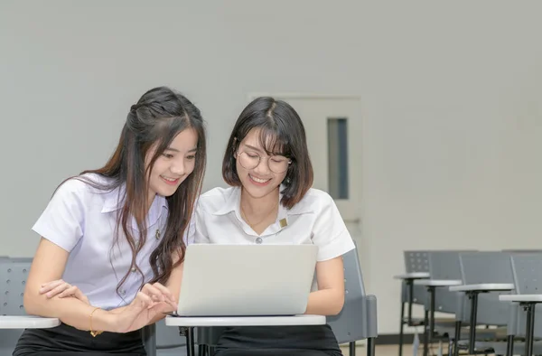 Studenti svegli in uniforme che lavorano con il computer portatile — Foto Stock