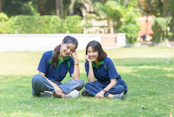 Felice carino studenti sorridono e seduti sull'erba — Foto Stock