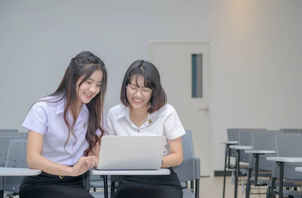 Милі студенти в уніформі посмішки і роботи з ноутбуком — стокове фото