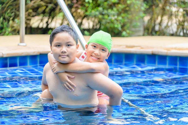 Bruder hält Schwester im Schwimmbad auf dem Rücken — Stockfoto