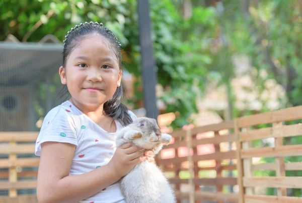 Felice ragazza carina abbraccio coniglio in fattoria . — Foto Stock