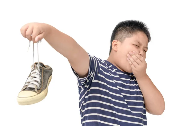Disgusted fat boy holding a pair of smelly shoes — Stock Photo, Image