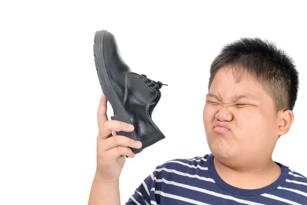 Menino enojado segurando um par de sapatos de couro fedorentos — Fotografia de Stock