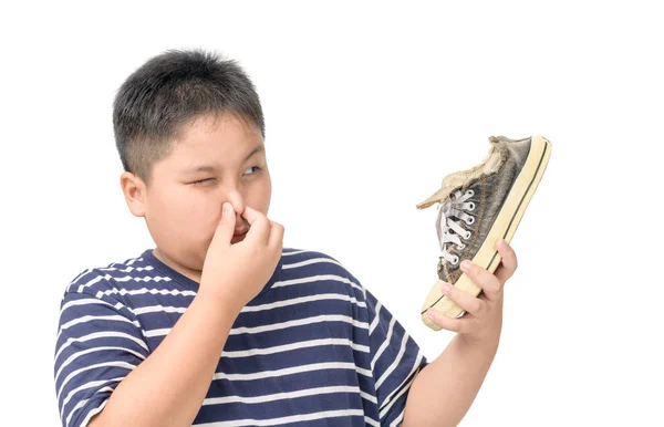 Disgusted fat boy holding a pair of smelly shoes — Stock Photo, Image