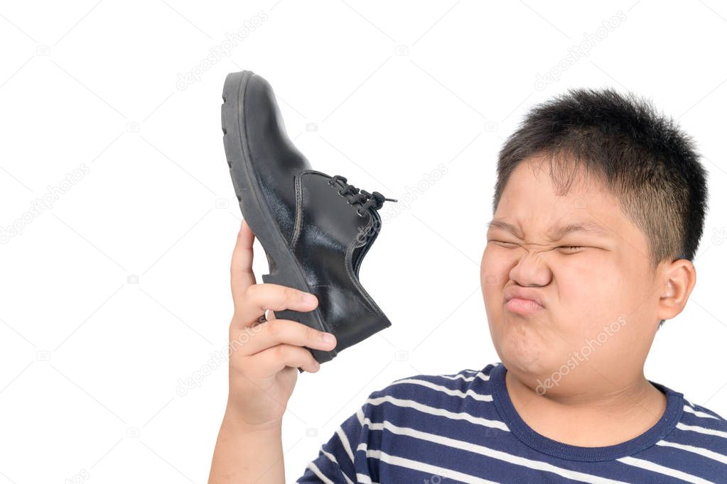 Disgusted boy holding a pair of smelly leather shoes 