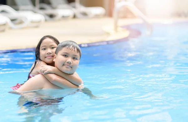 Hermano y hermana juegan agua en la piscina — Foto de Stock