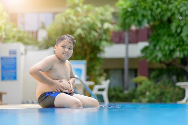 Fettleibige dicke Junge sitzen auf Schwimmbad — Stockfoto