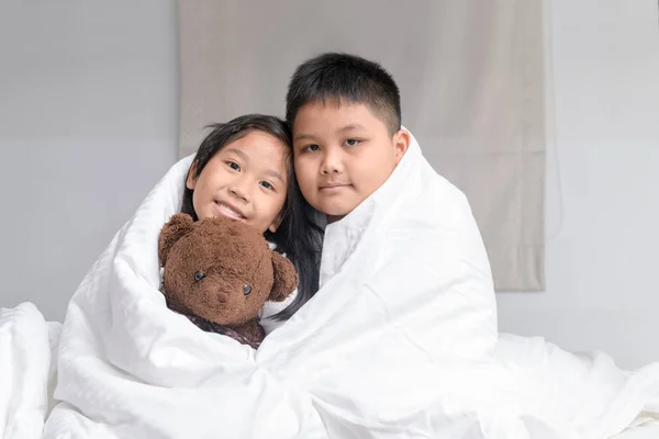 brother hug sister under blanket