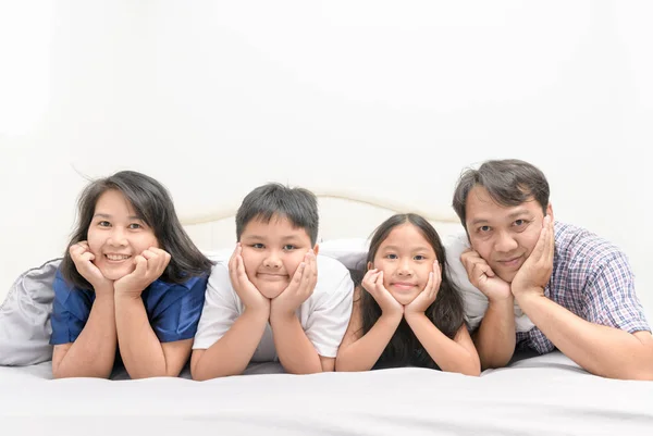 Азіатський щаслива молода родина лежала в ліжку разом — стокове фото