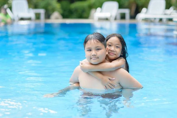 Irmão e irmã brincam de água na piscina — Fotografia de Stock
