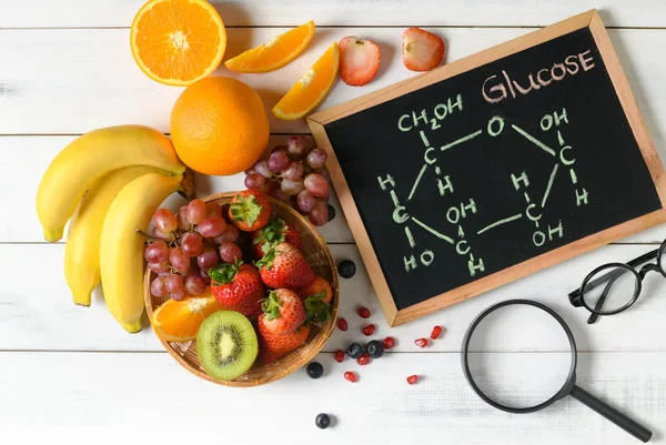 Glucose molecule on blackboard with mixed fresh fruits