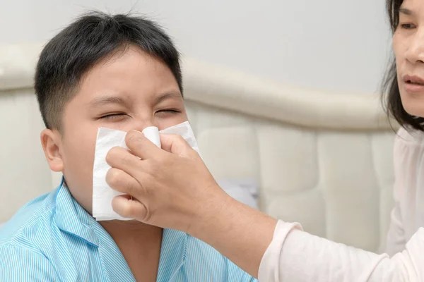 Sjukt asiatiskt barn som torkar eller rengör näsan med vävnad — Stockfoto