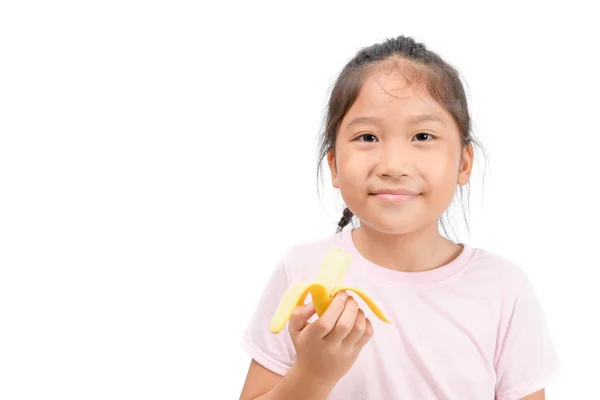 Malá Asijská roztomilá holka, která žere banánovou izolaci na bílém — Stock fotografie