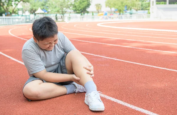 Asian fat boy holding his sports leg injury. muscle painful