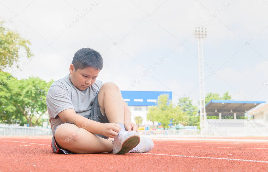 Obese boy tying shoe laces prepare to run. 