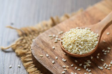 Tahta masadaki tahta kaşıkta beyaz susam tohumları. Beyaz susam, kalsiyum ve fosfor açısından zengindir. Kemiklerin ve dişlerin güçlenmesine yardımcı olur.