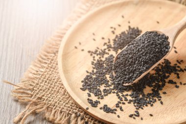 Tahta kaşıkta siyah susam tohumu. Siyah susamın faydaları saç köklerinin güçlenmesine ve parlamasına yardımcı olur. Enerjiyi artırır ve yanmaya ve zayıflamaya yardımcı olur