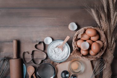 Ahşap zemin üzerinde hamur işleri için mutfak gereçleri olan taze yumurta ve kek unu, pasta ve fırın konseptine hazır olun.