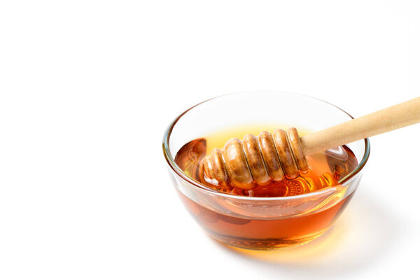 Honey with wooden honey dipper in bowl isolated on white background with copy space