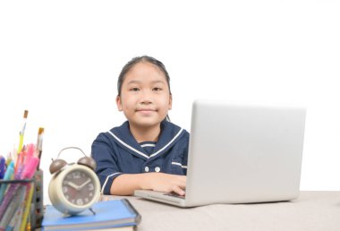 Bilgisayarla ödev yapan küçük Asyalı kız beyaz arka planda izole edilmiş, Covid-19 Coronavirus ve evden öğrenme, ev okulu konsepti