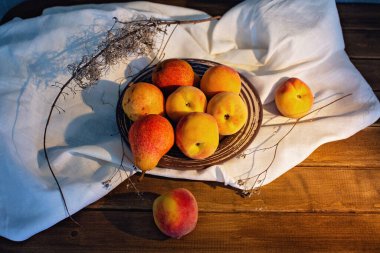 Meyveli, şeftalili, beyaz masa örtülü bir masa.