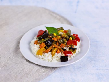 Mavi arka planda beyaz tabakta sebzeli pilav.