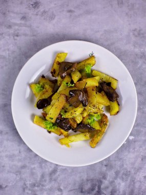 Beyaz tabakta mantarlı kızarmış patates.