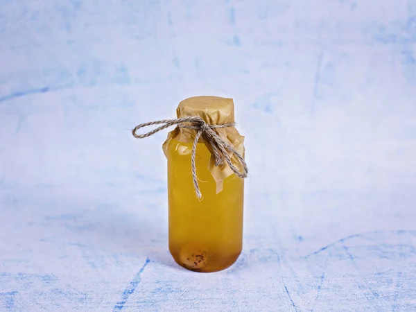 A jar of yellow juice on a blue background