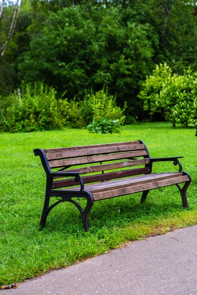 公園内の緑の芝生の上に木製のベンチ ストックフォト